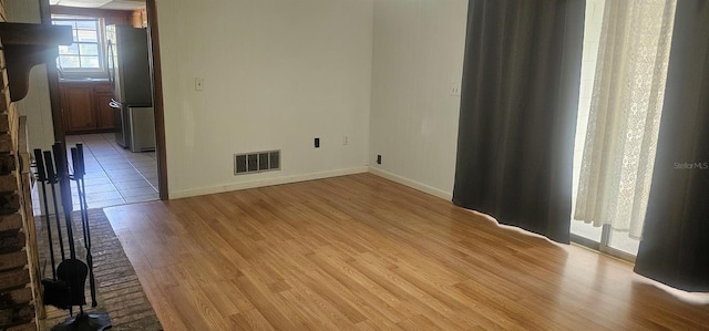 empty room featuring visible vents, light wood-style flooring, and baseboards