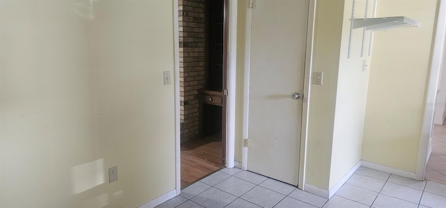 hall featuring baseboards and light tile patterned flooring