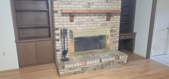 details featuring a brick fireplace, baseboards, and wood finished floors