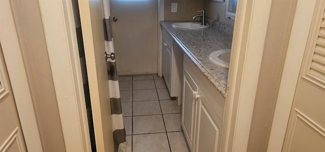 full bath featuring tile patterned floors, double vanity, and a sink