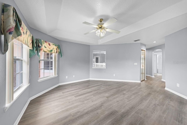 1802 Imperial Palm Dr, Apopka, FL 32712 - empty room with a raised ceiling, ceiling fan, arched walkways, baseboards, and wood finished floors