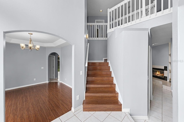 1802 Imperial Palm Dr, Apopka, FL 32712 - stairway featuring wood finished floors, a glass covered fireplace, a chandelier, baseboards, and arched walkways