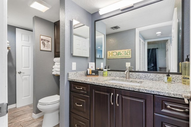3221 White Ibis Ct Unit C1, Punta Gorda, FL 33950 - bathroom with wood finished floors, toilet, vanity, a textured wall, and baseboards