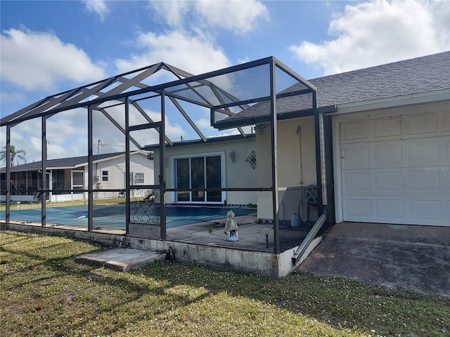 4299 Bullard St, North Port, FL 34287 - rear view of house with a garage, a lawn, a shingled roof, glass enclosure, and stucco siding