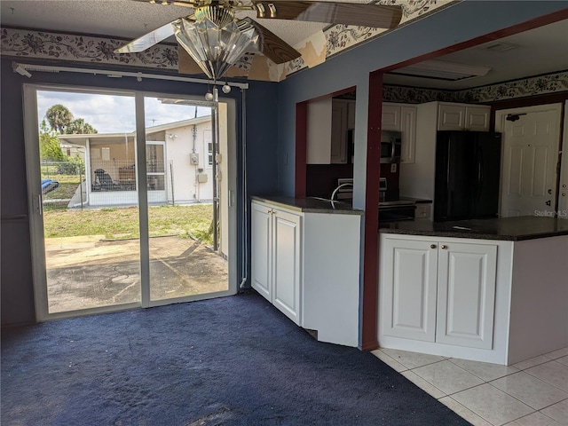 4299 Bullard St, North Port, FL 34287 - kitchen with freestanding refrigerator, white cabinets, dark countertops, and light colored carpet