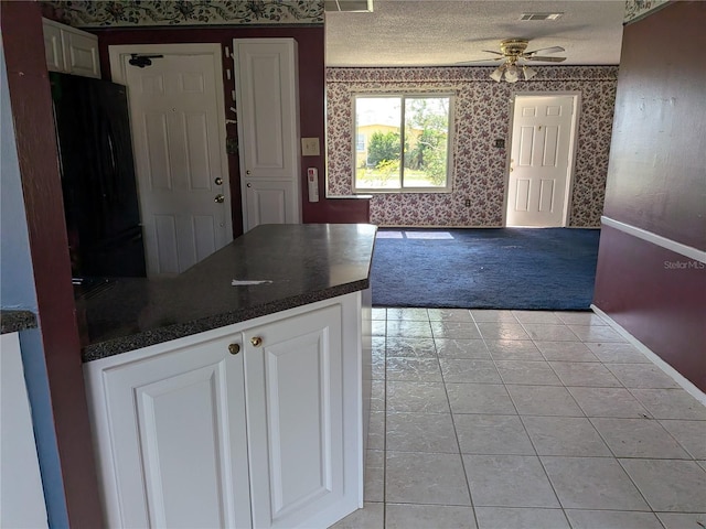 4299 Bullard St, North Port, FL 34287 - kitchen featuring wallpapered walls, freestanding refrigerator, a ceiling fan, dark countertops, and white cabinets