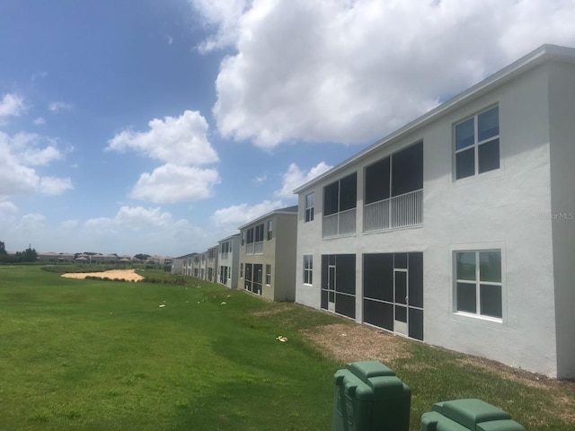 back of property with stucco siding and a yard