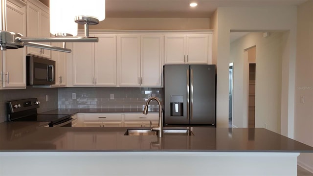 kitchen featuring stainless steel electric range oven, refrigerator with ice dispenser, a sink, backsplash, and white cabinets