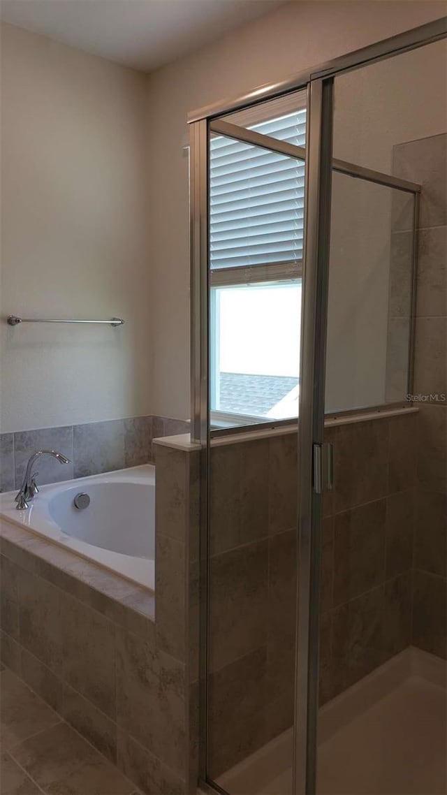 bathroom featuring a garden tub and a shower stall