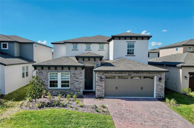 prairie-style home featuring stone siding, a garage, stucco siding, a shingled roof, and decorative driveway