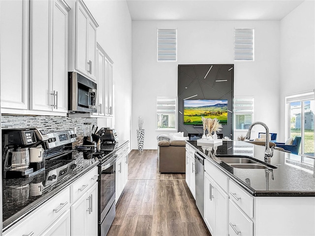 kitchen featuring visible vents, a sink, wood finished floors, stainless steel appliances, and an island with sink