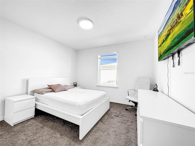 bedroom with dark colored carpet and baseboards