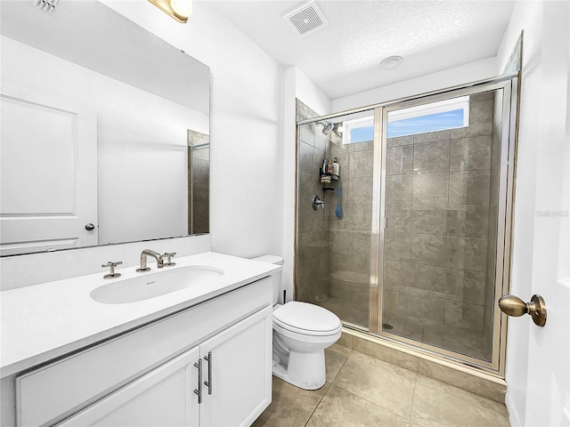 bathroom with a stall shower, toilet, tile patterned flooring, vanity, and a textured ceiling