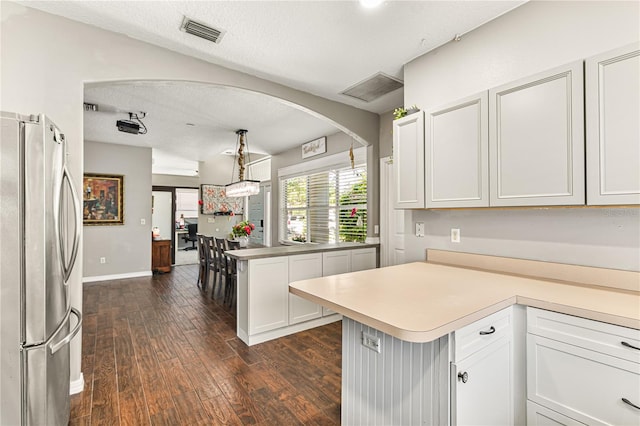 2623 Gables Dr, Eustis, FL 32726 - kitchen with freestanding refrigerator, a peninsula, dark wood-type flooring, light countertops, and arched walkways