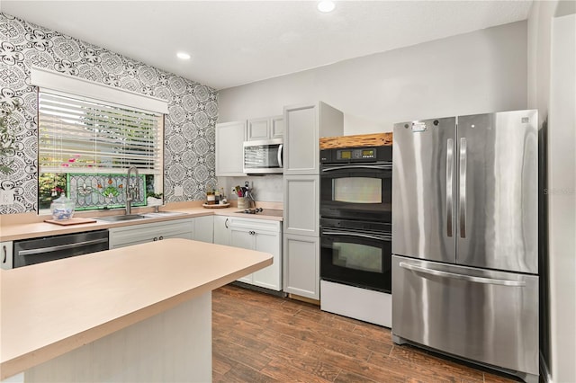 2623 Gables Dr, Eustis, FL 32726 - kitchen with black appliances, a sink, light countertops, dark wood-style flooring, and wallpapered walls