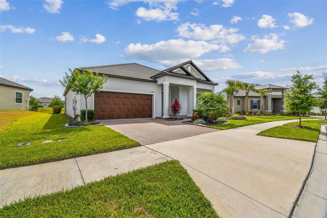31840 Magna Gulf Loop, San Antonio, FL 33576 - view of front of property with driveway, a garage, a front lawn, stucco siding, and a tiled roof