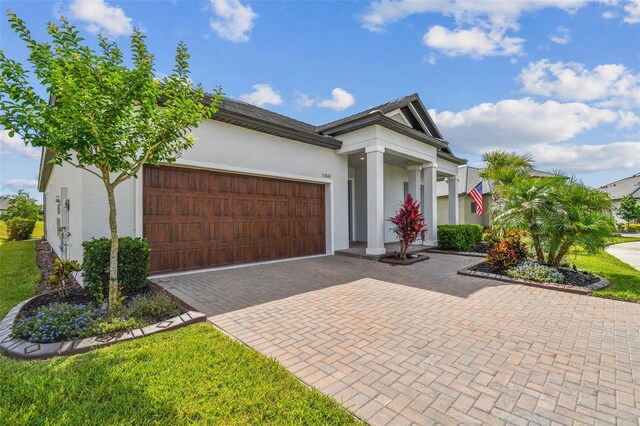 31840 Magna Gulf Loop, San Antonio, FL 33576 - view of front of house with an attached garage, stucco siding, decorative driveway, and a front lawn