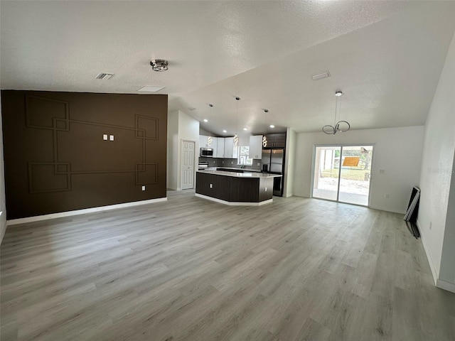 3082 SE 140th Ln, Summerfield, FL 34491 - unfurnished living room with a notable chandelier, baseboards, light wood finished floors, visible vents, and vaulted ceiling