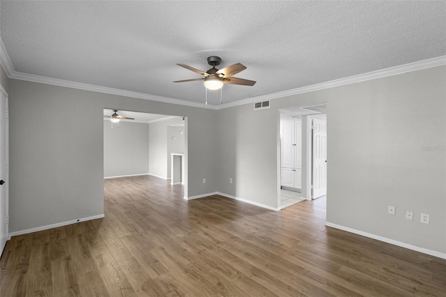 unfurnished room featuring a ceiling fan, wood finished floors, crown molding, a textured ceiling, and baseboards