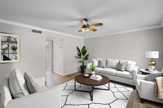 living room featuring wood finished floors, ceiling fan, ornamental molding, baseboards, and a textured ceiling