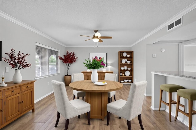 dining area featuring a ceiling fan, light wood-style flooring, ornamental molding, a textured ceiling, and baseboards
