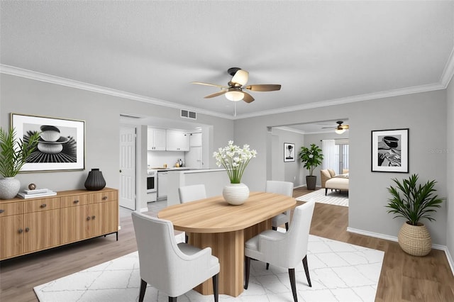 dining space featuring ceiling fan, light wood finished floors, ornamental molding, and baseboards