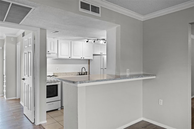 kitchen with white appliances, a textured ceiling, white cabinets, baseboards, and crown molding