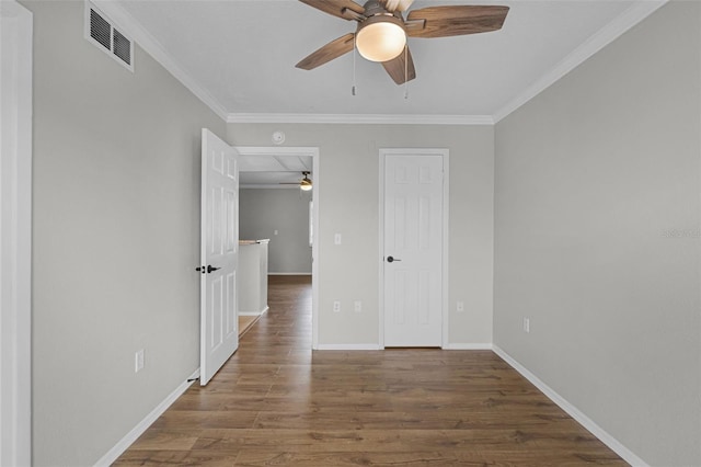 empty room featuring ceiling fan, wood finished floors, ornamental molding, and baseboards