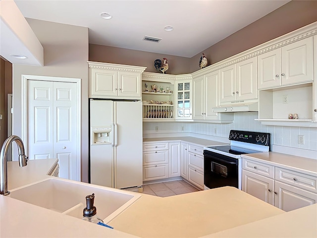 502 Canopy Ln, Lady Lake, FL 32159 - kitchen with white fridge with ice dispenser, electric range, open shelves, under cabinet range hood, and white cabinets