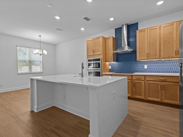 8018 Colby Cir, Orlando, FL 32817 - kitchen with wall chimney range hood, stainless steel double oven, dark wood-style flooring, light countertops, and a center island with sink