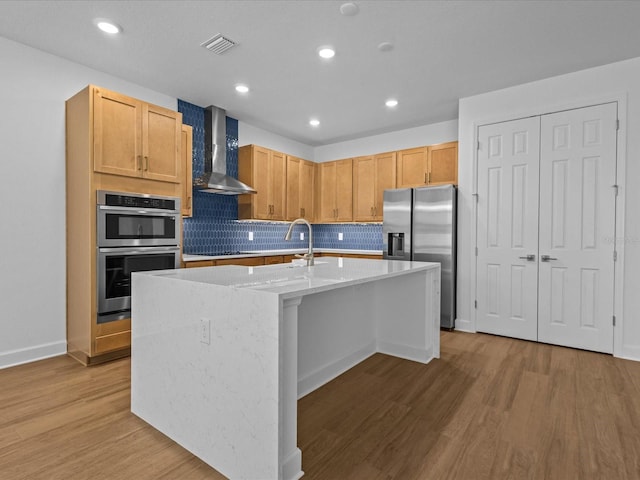 8018 Colby Cir, Orlando, FL 32817 - kitchen featuring appliances with stainless steel finishes, wall chimney exhaust hood, wood finished floors, an island with sink, and tasteful backsplash