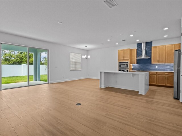 8018 Colby Cir, Orlando, FL 32817 - kitchen with wall chimney range hood, appliances with stainless steel finishes, a chandelier, tasteful backsplash, and light wood finished floors