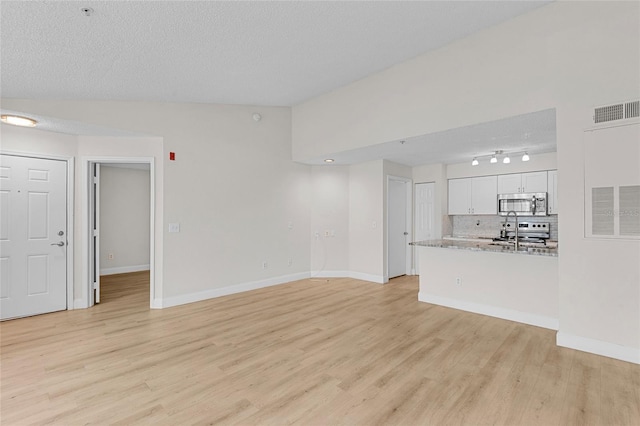 2213 Grand Cayman Ct Unit 1138, Kissimmee, FL 34741 - unfurnished living room featuring light wood-type flooring, a textured ceiling, baseboards, and rail lighting