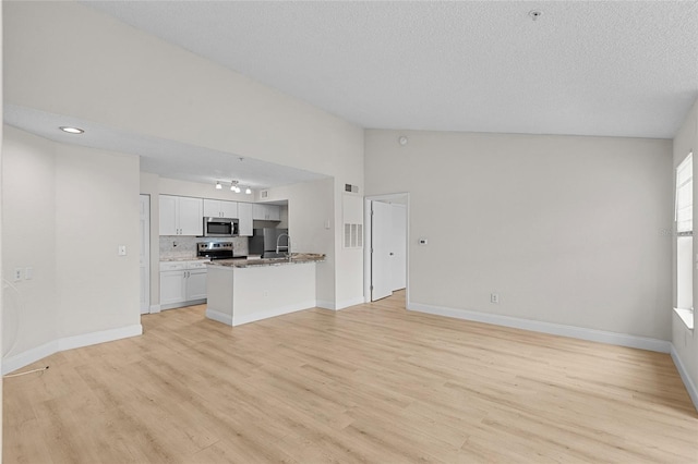 2213 Grand Cayman Ct Unit 1138, Kissimmee, FL 34741 - unfurnished living room featuring light wood finished floors, a textured ceiling, baseboards, vaulted ceiling, and rail lighting