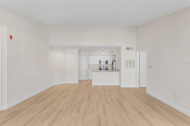 2213 Grand Cayman Ct Unit 1138, Kissimmee, FL 34741 - unfurnished living room with light wood-style floors, baseboards, and a textured ceiling