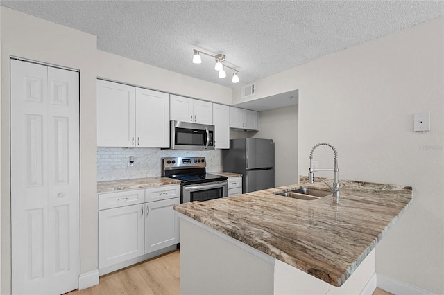 2213 Grand Cayman Ct Unit 1138, Kissimmee, FL 34741 - kitchen featuring stainless steel appliances, a sink, a peninsula, light stone counters, and light wood-style floors