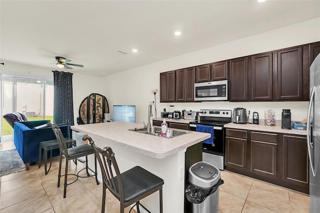 1401 Yellow Finch Dr, Davenport, FL 33837 - kitchen with stainless steel appliances, a sink, light tile patterned floors, light countertops, and a kitchen bar