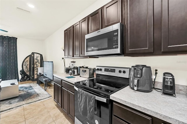 1401 Yellow Finch Dr, Davenport, FL 33837 - kitchen featuring stainless steel appliances, light countertops, dark brown cabinets, and light tile patterned floors