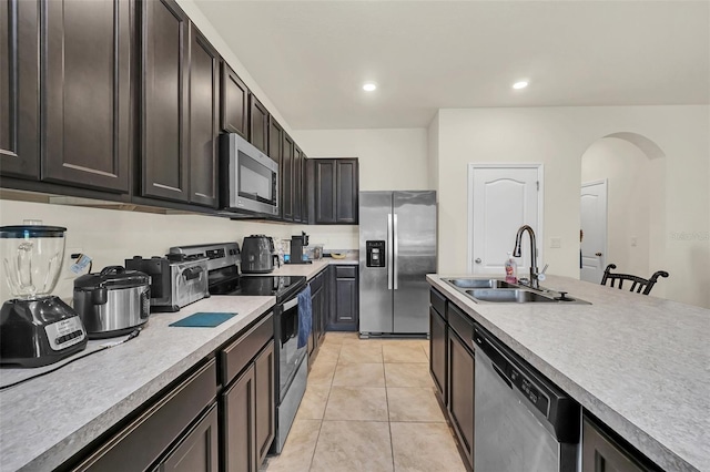 1401 Yellow Finch Dr, Davenport, FL 33837 - kitchen featuring appliances with stainless steel finishes, a sink, arched walkways, light tile patterned floors, and light countertops