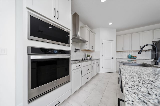 2591 Seagirt Way, Clermont, FL 34711 - kitchen featuring appliances with stainless steel finishes, wall chimney exhaust hood, a sink, decorative backsplash, and light stone counters