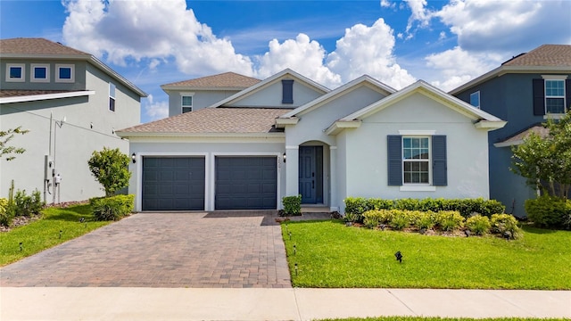 2591 Seagirt Way, Clermont, FL 34711 - traditional home featuring a garage, decorative driveway, stucco siding, a front lawn, and roof with shingles