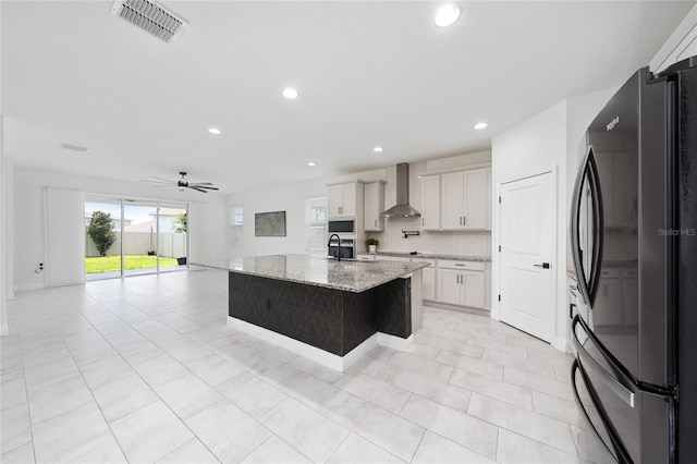 2591 Seagirt Way, Clermont, FL 34711 - kitchen with freestanding refrigerator, wall chimney range hood, plenty of natural light, ceiling fan, and recessed lighting
