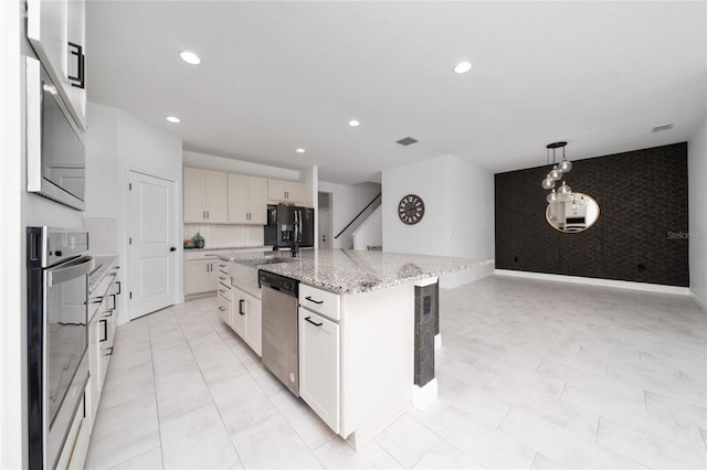 2591 Seagirt Way, Clermont, FL 34711 - kitchen featuring appliances with stainless steel finishes, an accent wall, a kitchen island with sink, wallpapered walls, and recessed lighting