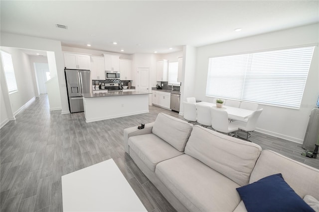 living area featuring recessed lighting, baseboards, and light wood finished floors