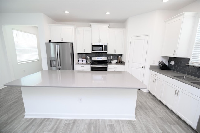 kitchen featuring stainless steel appliances, a kitchen island, backsplash, white cabinets, and recessed lighting