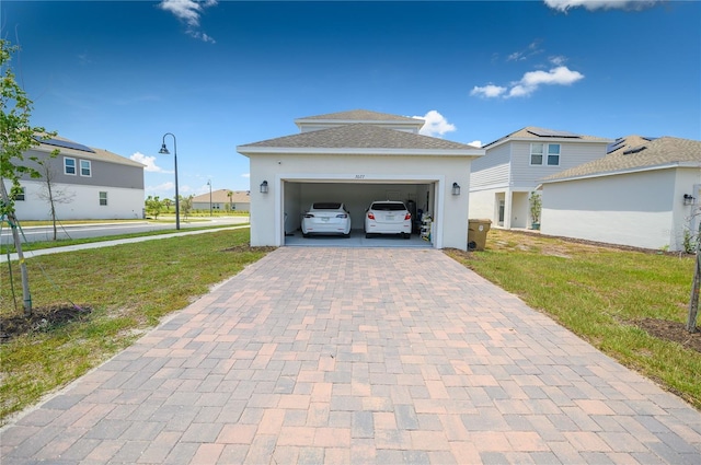 view of front of house featuring decorative driveway, a front yard, an attached garage, stucco siding, and a shingled roof