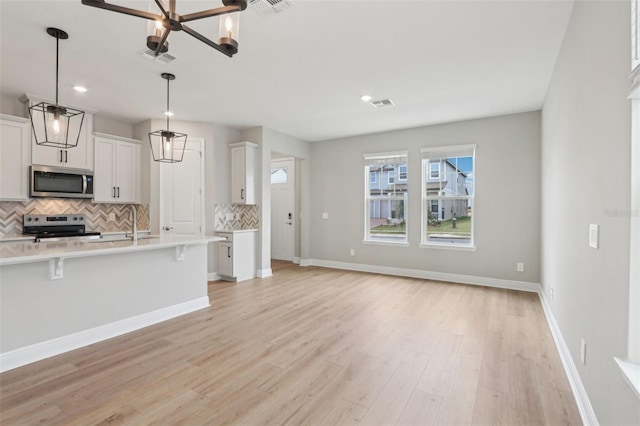 16460 Silver Brook Way, Winter Garden, FL 34787 - kitchen featuring stainless steel appliances, tasteful backsplash, light countertops, a kitchen bar, and white cabinets