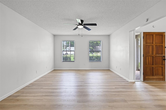 spare room featuring ceiling fan, a textured ceiling, light wood-type flooring, and baseboards