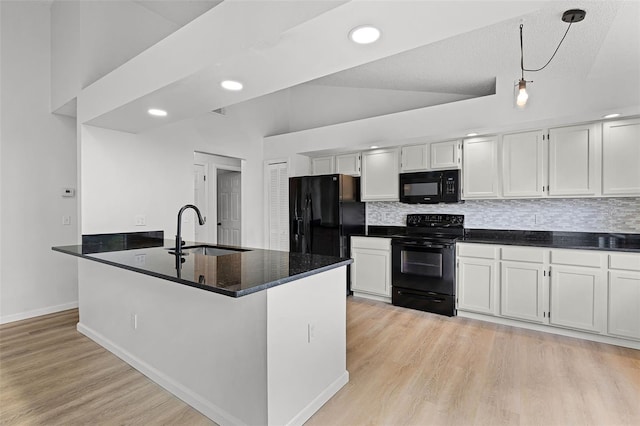kitchen featuring black appliances, a sink, light wood-style flooring, backsplash, and recessed lighting