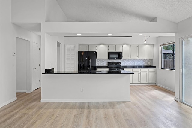 kitchen featuring black appliances, dark countertops, light wood-style flooring, baseboards, and lofted ceiling